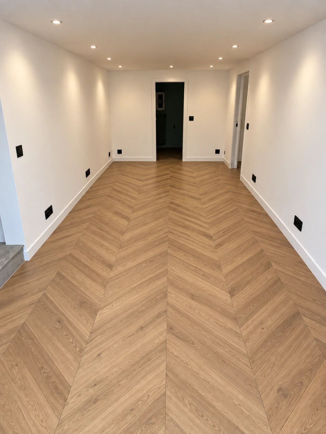 Plateau de bureaux rénové, parquet à chevrons, prises noires réparties le long des murs et spots encastrés au plafond