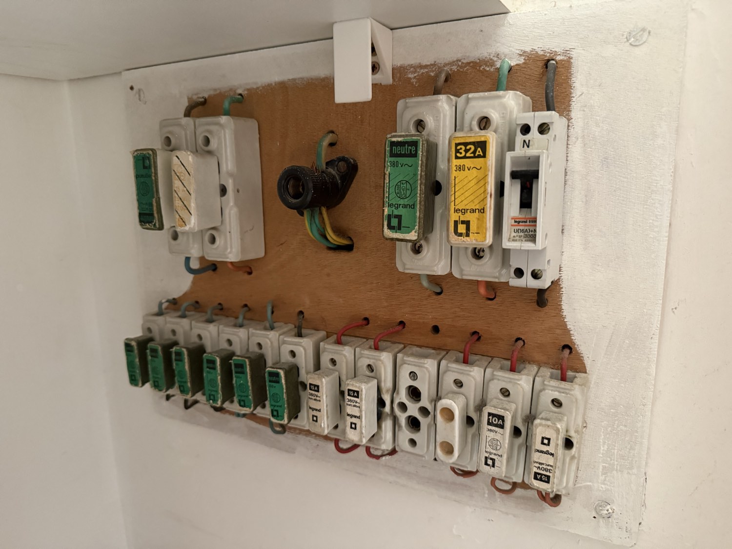 Tableau électrique vétuste à porte-fusibles en porcelaine, vissé sur une planche de bois, relevé lors d'une visite à Nice